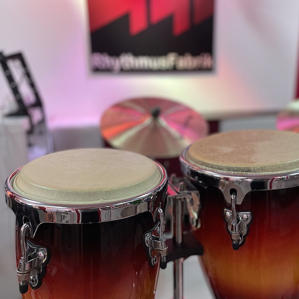 Dieses Bild zeigt zwei Mini Congas und im Hintergrund das Firmenlogo der RhythmusFabrik